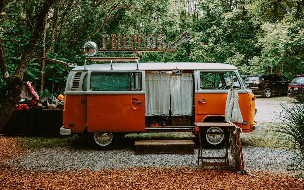 Orange-weißer Oldtimer-Bus als mobile Fotobox auf einem Kiesplatz im Grünen