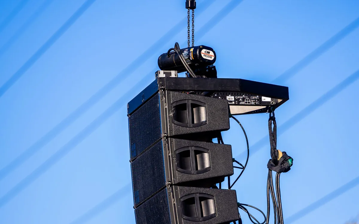 Line-Array-Lautsprecher, an einer Traverse vor blauem Himmel aufgehängt