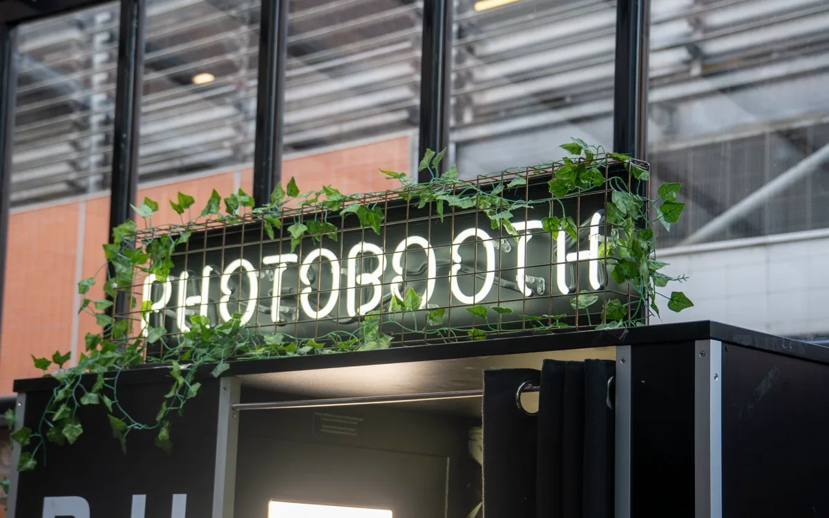 Leuchtschrift Photobooth mit Efeu über dem Eingang einer Fotobox
