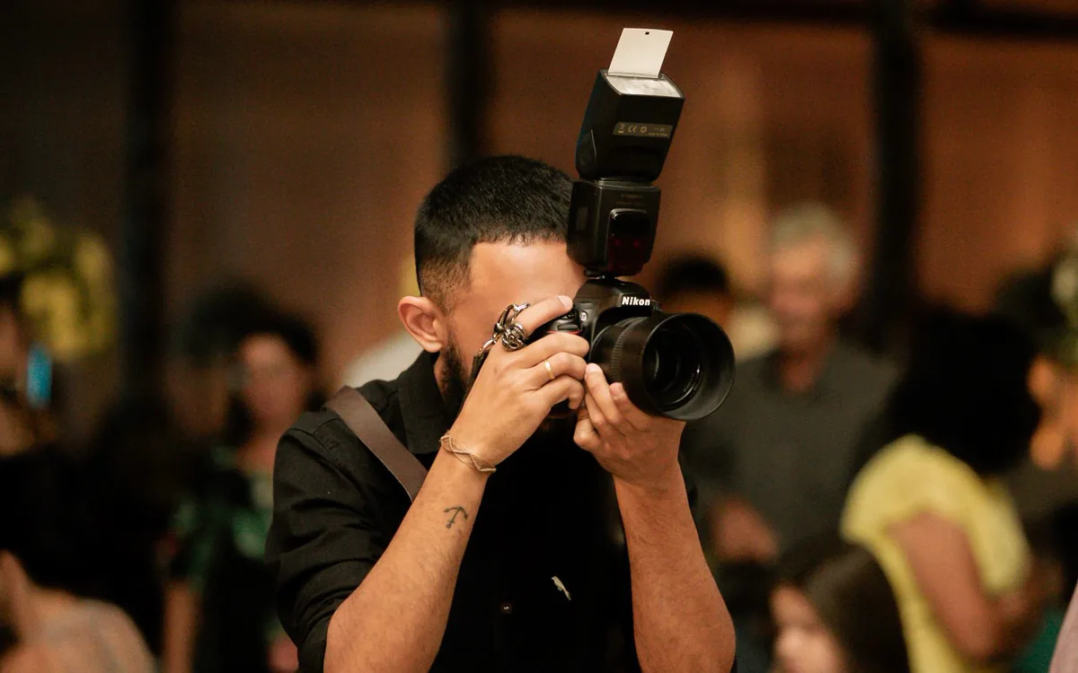 Fotograf mit Spiegelreflexkamera und Aufsteckblitz bei einer Veranstaltung