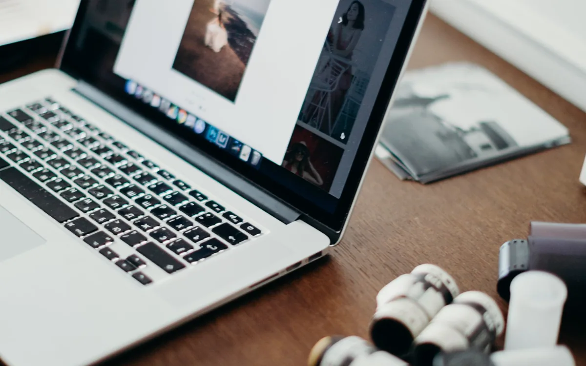 Laptop mit einer Bildergalerie-Seite neben Filmdosen auf einem Schreibtisch